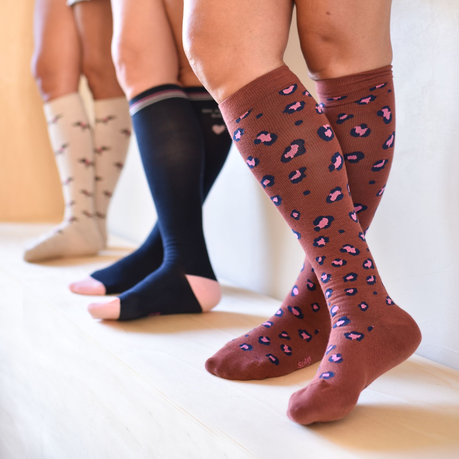 Les trois modèles de chaussettes de compression Sister Feel portés : léopard, bleu et teckels